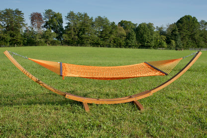 Orange Jumbo Rope Hammock hanging on a Wood Arc Hammock Stand in an open grass field.