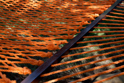 Close view of the varnished wood spreader bar and Orange polyester rope of the Jumbo Rope Hammock.