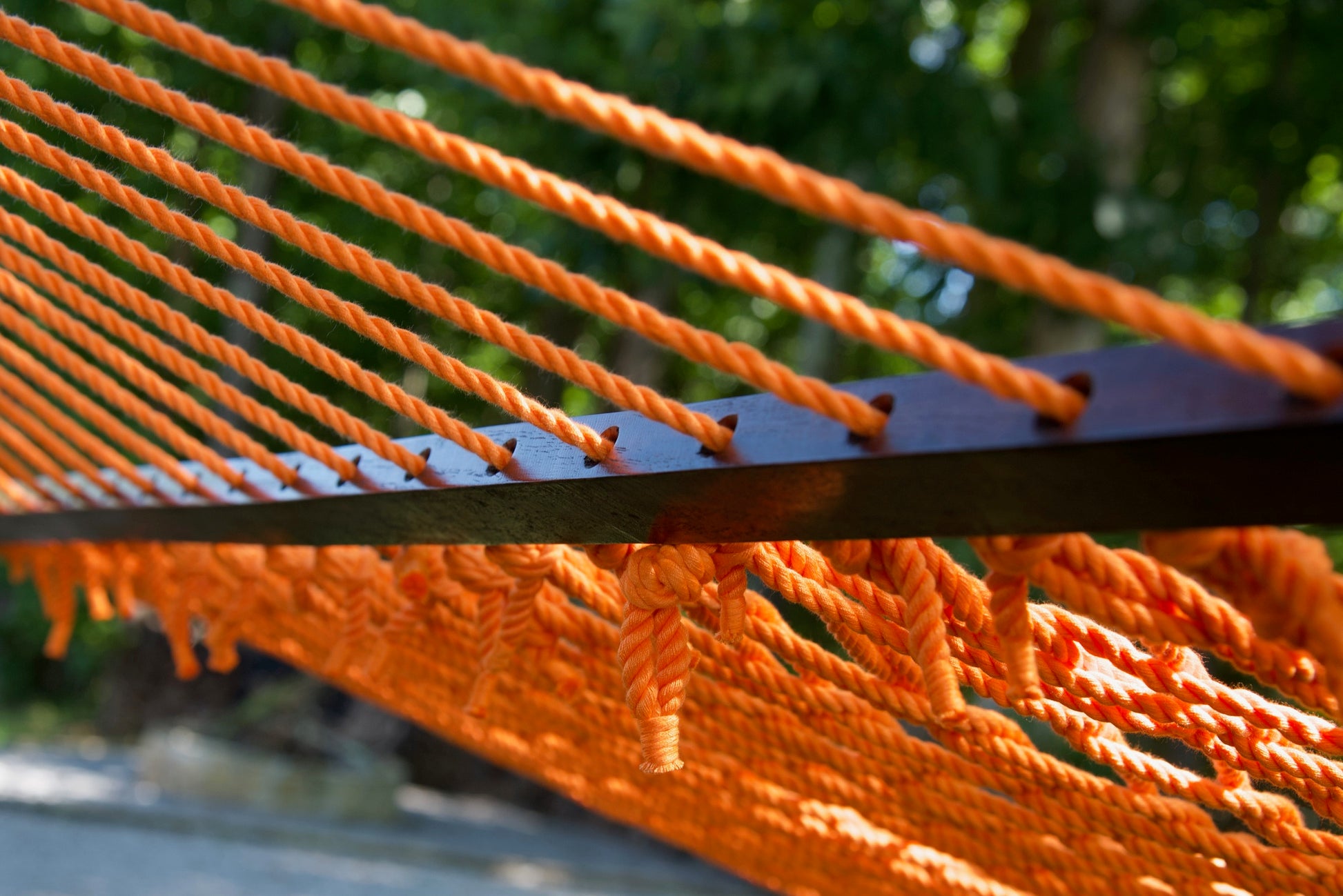 Close view of the Orange end cords threaded through the wood spreader bar of the Jumbo Rope Hammock.