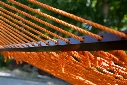 Close view of the Orange end cords threaded through the wood spreader bar of the Jumbo Rope Hammock.