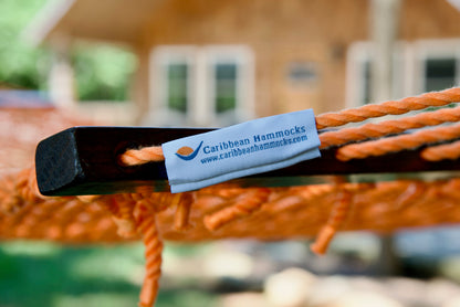 Caribbean Hammocks brand label on the wood spreader bar of the Orange Jumbo Rope Hammock.
