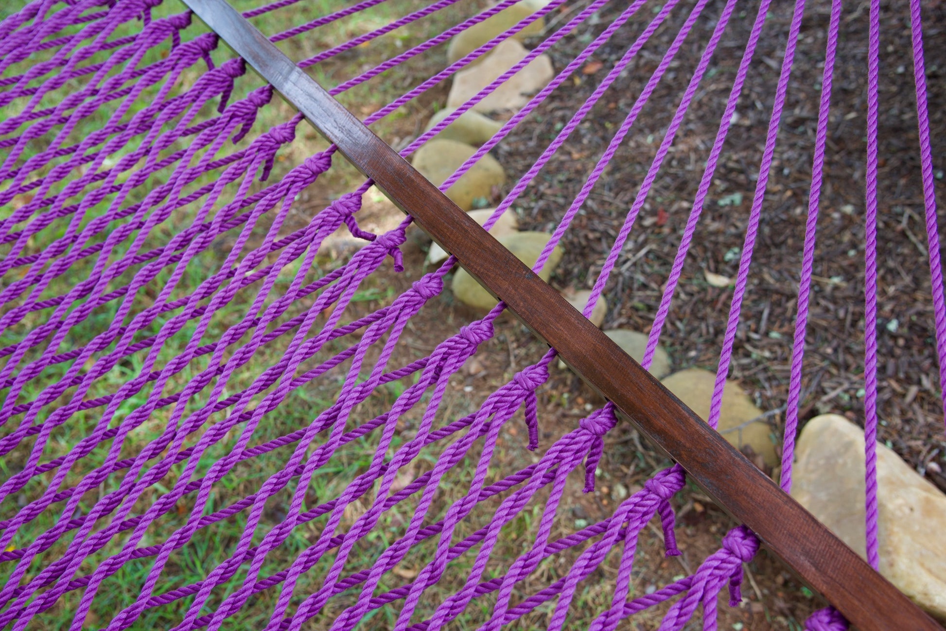 Close view of the varnished wood spreader bar and Purple polyester rope of the Jumbo Rope Hammock.