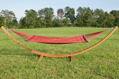 Red Jumbo Rope Hammock hanging on a Wood Arc Hammock Stand in an open grass field.