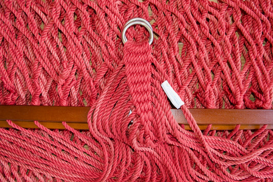 Close view of the gathered Red end cords and O-rings of the Jumbo Rope Hammock above the wood spreader bar.