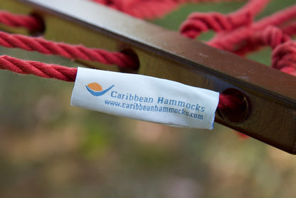 Caribbean Hammocks brand label on the wood spreader bar of the Red Jumbo Rope Hammock.