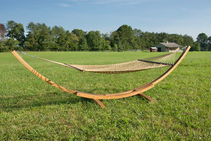 Tan Jumbo Rope Hammock hanging on a Wood Arc Hammock Stand in an open grass field.
