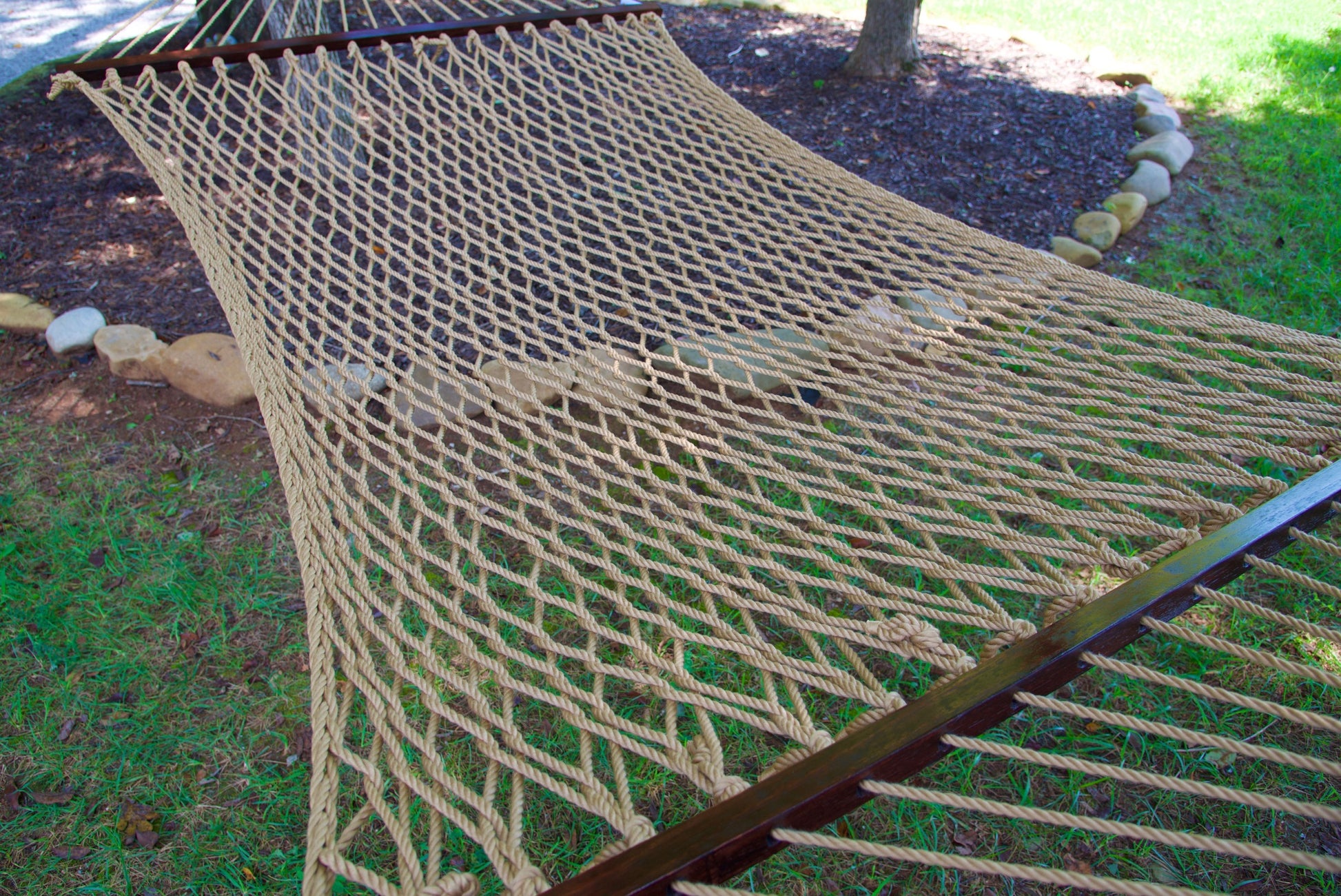 Close view of the Tan polyester rope bed and wood spreader bar of the Jumbo Rope Hammock.