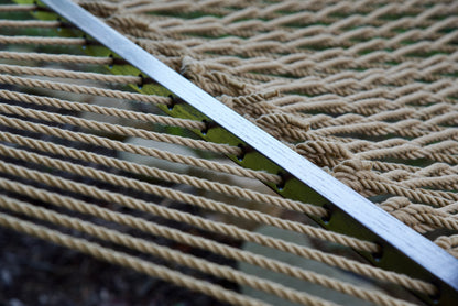 Close view of the varnished wood spreader bar and Tan polyester rope of the Jumbo Rope Hammock.