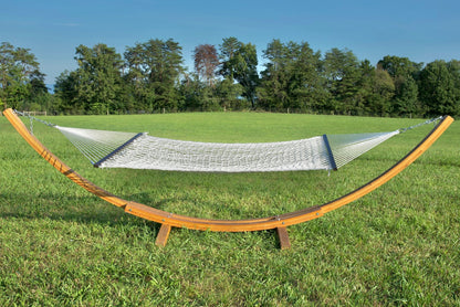 White Jumbo Rope Hammock hanging on a Wood Arc Hammock Stand in an open grass field.