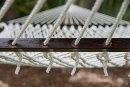 Close view of the White end cords threaded through the wood spreader bar of the Jumbo Rope Hammock.