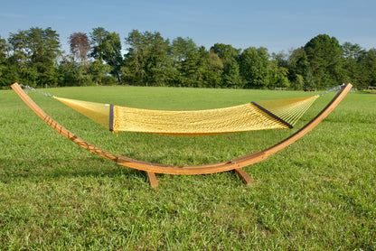 Yellow Jumbo Rope Hammock hanging on a Wood Arc Hammock Stand in an open grass field.