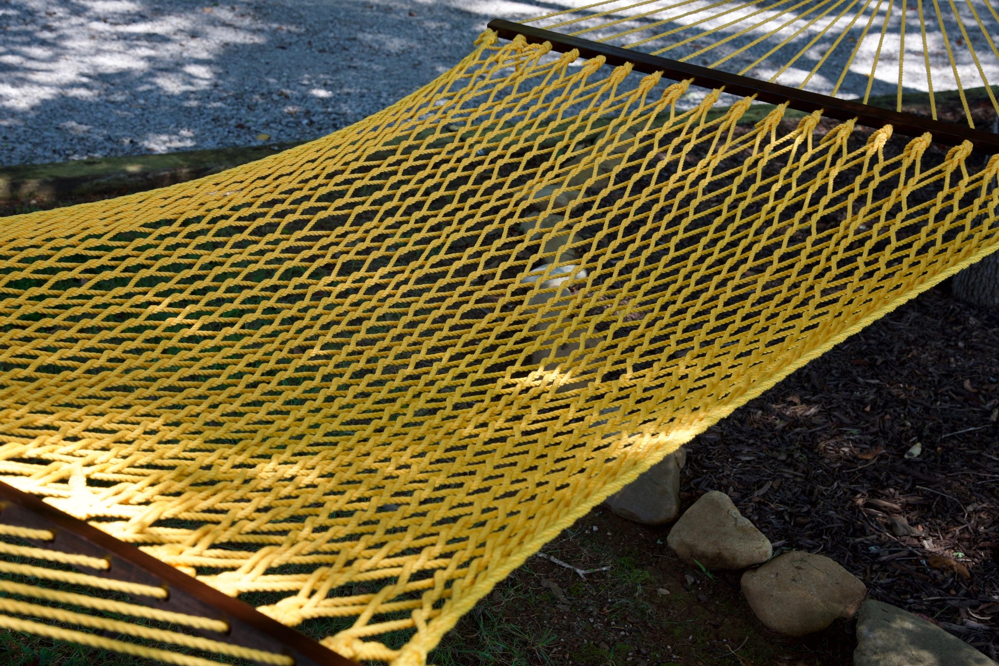 Close view of the Yellow polyester rope bed and wood spreader bar of the Jumbo Rope Hammock.
