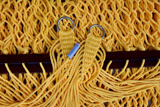 Close view of the gathered Yellow end cords and O-rings of the Jumbo Rope Hammock above the wood spreader bar.