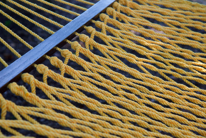 Close view of the varnished wood spreader bar and Yellow polyester rope of the Jumbo Rope Hammock.