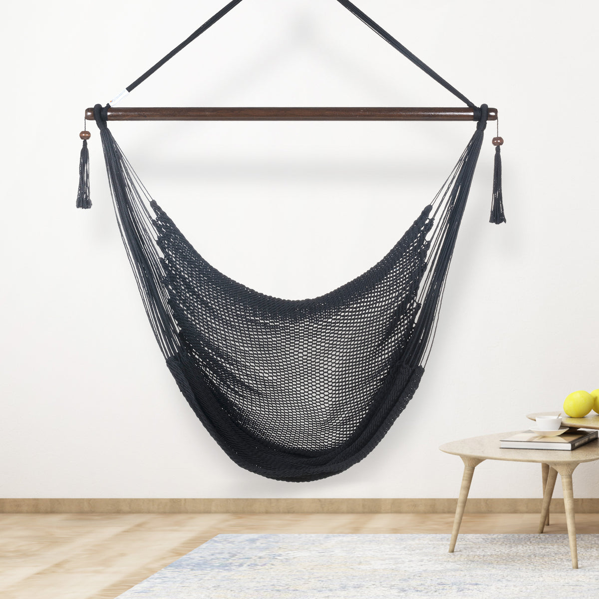 Black Large Caribbean Hammock Chair hanging indoors beside a small round side table against a cream wall