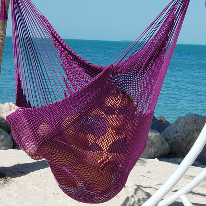 Woman lying back in a purple Large Caribbean Hammock Chair on a white arc stand overlooking turquoise water