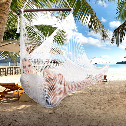 Woman lying back in a white Large Caribbean Hammock Chair on a tropical beach with loungers and palm fronds