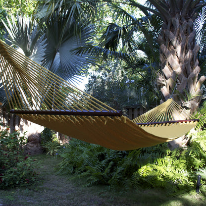 Yellow Double Caribbean Hammock hanging between palms in a tropical garden