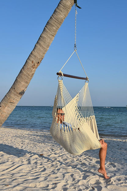 Man relaxing in a cream Jumbo Caribbean Hammock Chair hung from a leaning palm tree on a beach