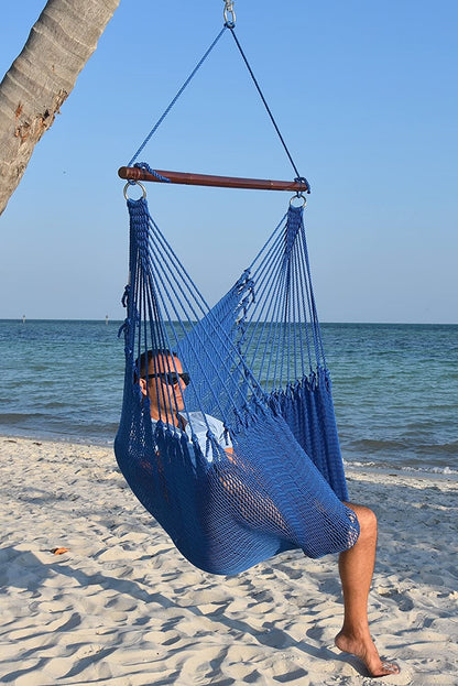 Man in sunglasses seated in a dark blue Jumbo Caribbean Hammock Chair on a white sand beach