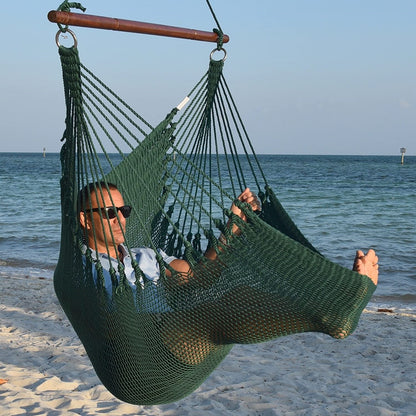 Man in sunglasses stretched out in a green Jumbo Caribbean Hammock Chair with calm ocean behind