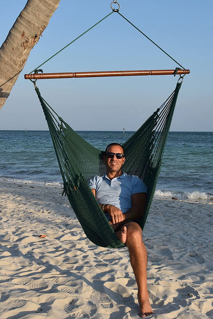 Man in sunglasses seated in a green Jumbo Caribbean Hammock Chair on a white sand beach