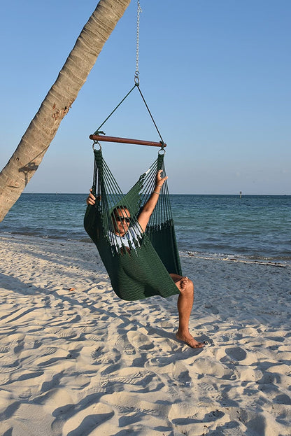 Man relaxing in a green Jumbo Caribbean Hammock Chair hung from a leaning palm tree on a beach