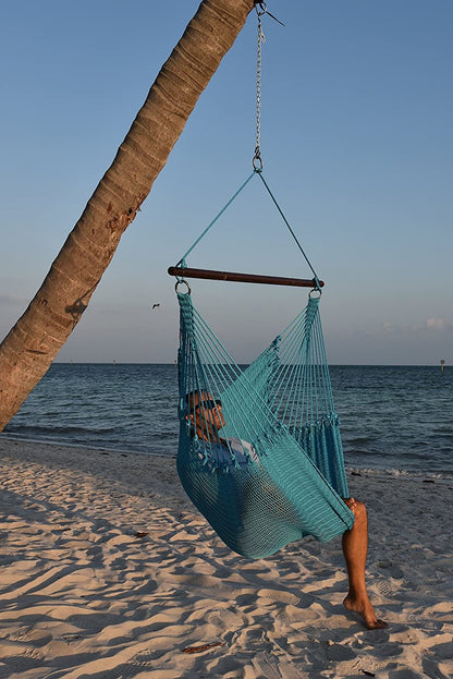 Man relaxing in a light blue Jumbo Caribbean Hammock Chair hung from a leaning palm tree on a beach