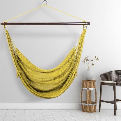 Olive Jumbo Caribbean Hammock Chair hanging beside a barrel side table and rattan stool against a pale grey wall