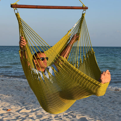 Man in sunglasses stretched out in an olive Jumbo Caribbean Hammock Chair with calm ocean behind