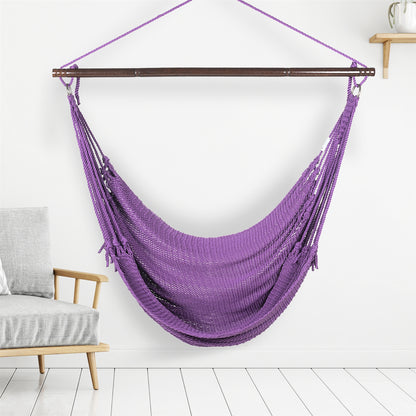 Purple Jumbo Caribbean Hammock Chair hanging indoors beside a pale wood armchair against a white wall