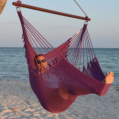 Man in sunglasses stretched out in a purple Jumbo Caribbean Hammock Chair with calm ocean behind