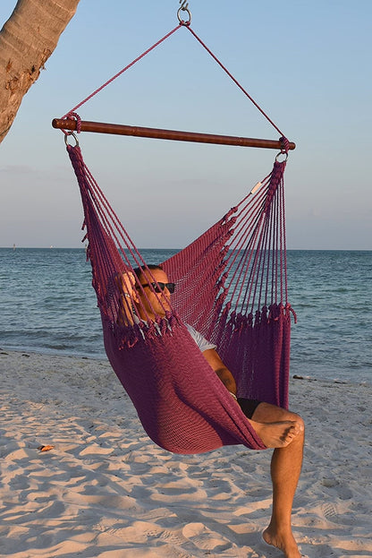 Man in sunglasses seated in a purple Jumbo Caribbean Hammock Chair on a white sand beach