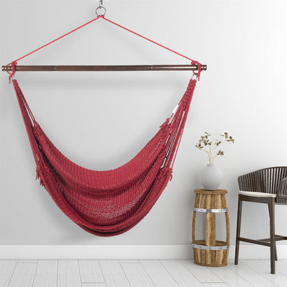Red Jumbo Caribbean Hammock Chair hanging beside a barrel side table and rattan stool against a pale grey wall