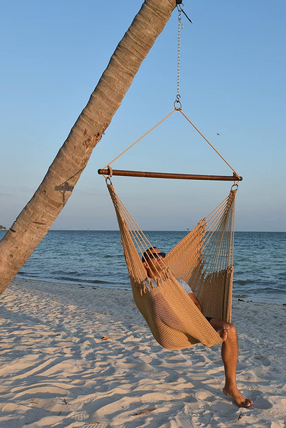 Man relaxing in a tan Jumbo Caribbean Hammock Chair hung from a leaning palm tree on a beach