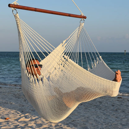 Man in sunglasses stretched out in a white Jumbo Caribbean Hammock Chair with calm ocean behind