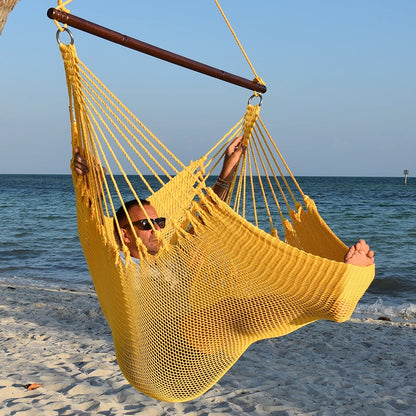Man in sunglasses stretched out in a yellow Jumbo Caribbean Hammock Chair with calm ocean behind