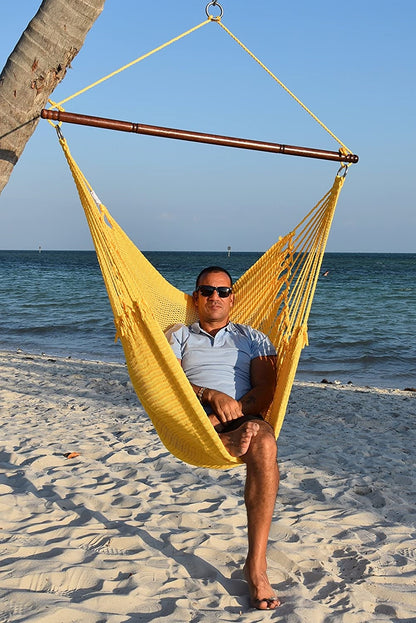 Man in sunglasses seated in a yellow Jumbo Caribbean Hammock Chair on a white sand beach