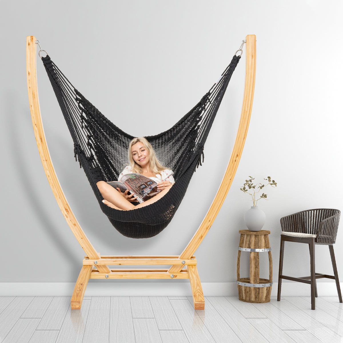 Black Jumbo Caribbean Recliner on a wood arc stand in a styled interior corner beside a woven barstool