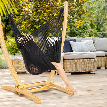 Black Jumbo Caribbean Recliner on a wood arc stand on a deck beside a wicker sofa