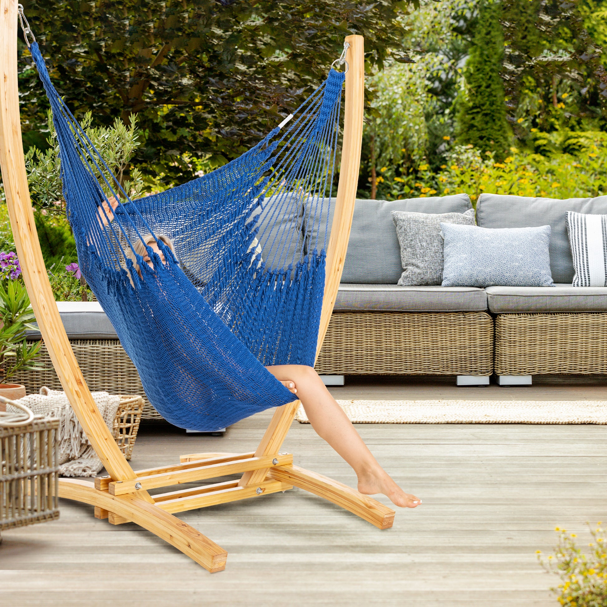Dark Blue Jumbo Caribbean Recliner on a wood arc stand on a deck beside a wicker sofa