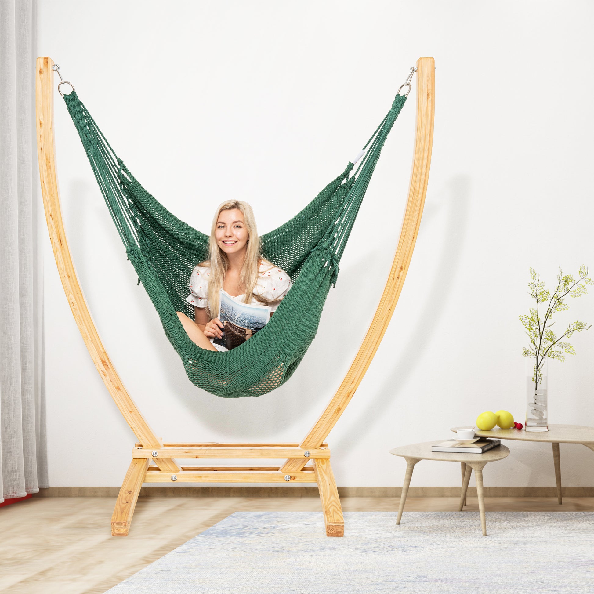Green Jumbo Caribbean Recliner on a wood arc stand in a living room beside a low round side table