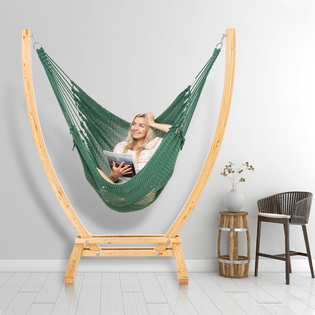 Green Jumbo Caribbean Recliner on a wood arc stand in a styled interior corner beside a woven barstool