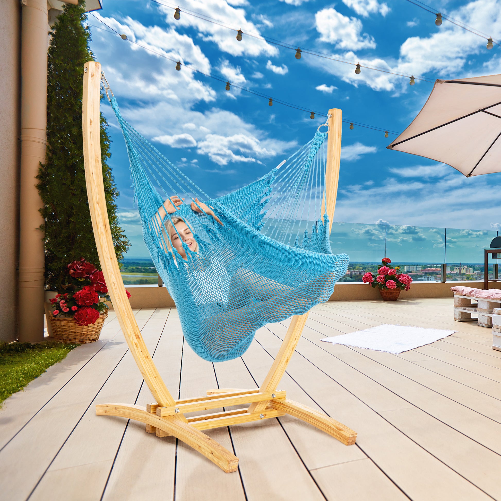 Light Blue Jumbo Caribbean Recliner on a wood arc stand on a rooftop deck under string lights and a patio umbrella