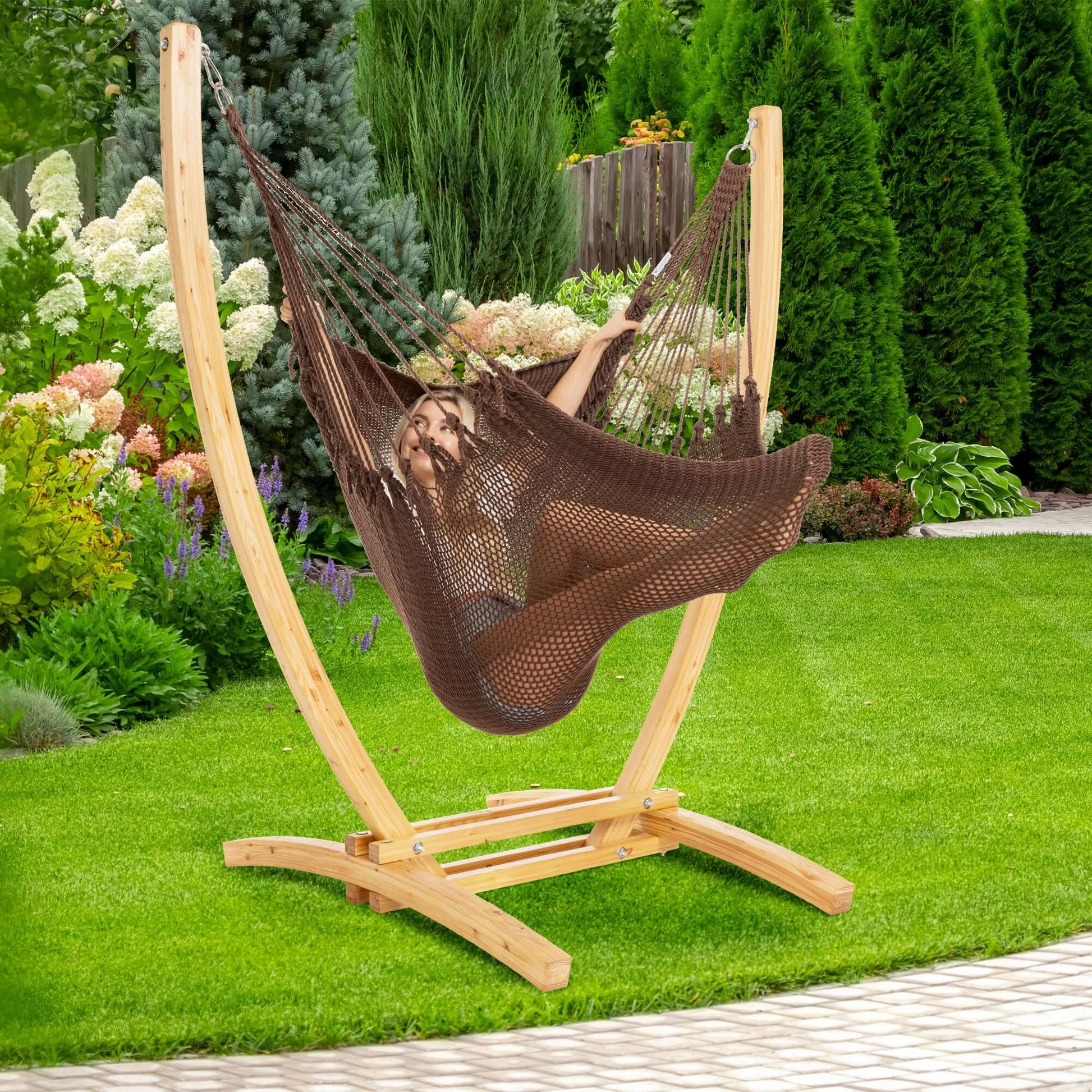 Mocha Jumbo Caribbean Recliner on a wood arc stand in a backyard beside flowering hydrangeas