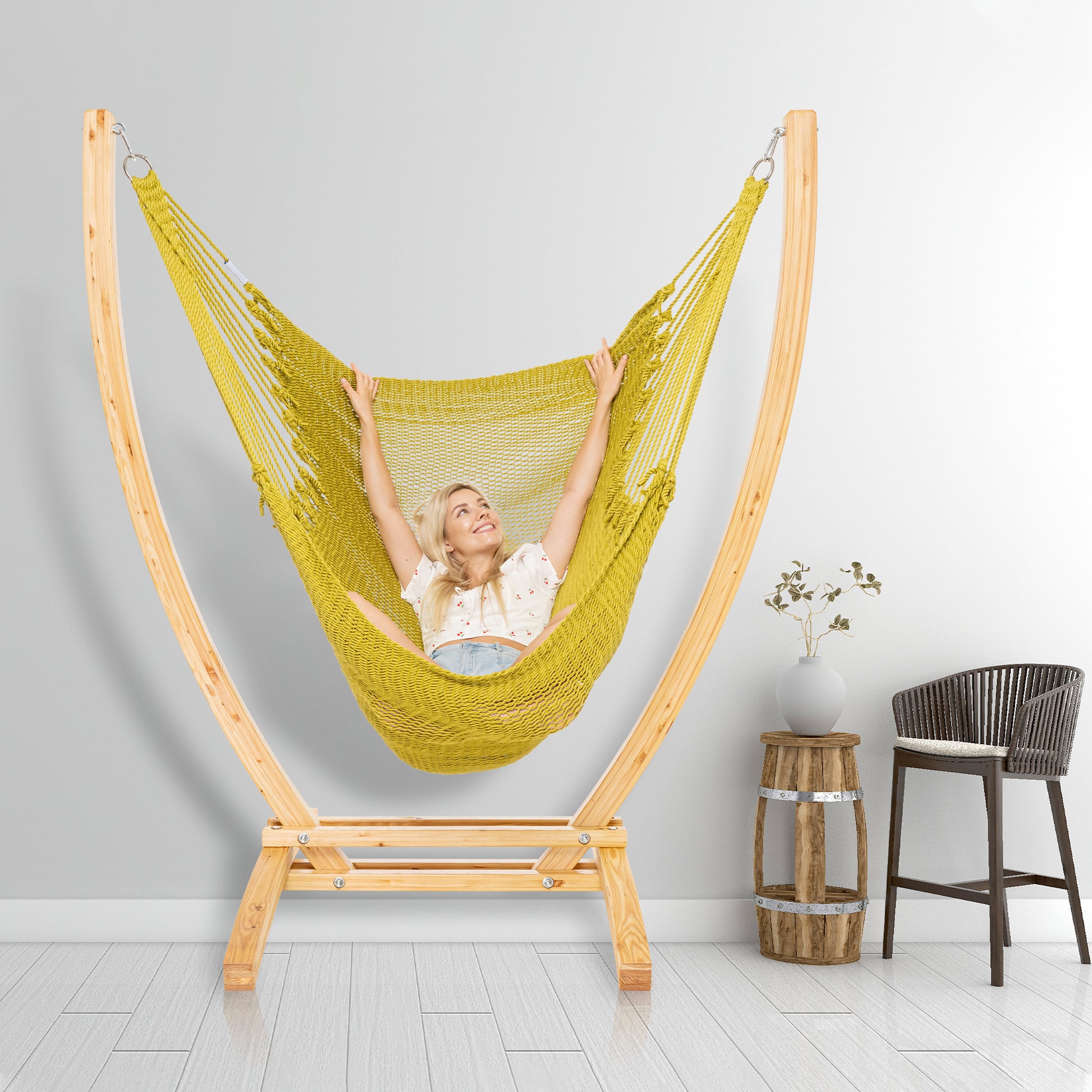 Olive Jumbo Caribbean Recliner on a wood arc stand in a styled interior corner beside a woven barstool