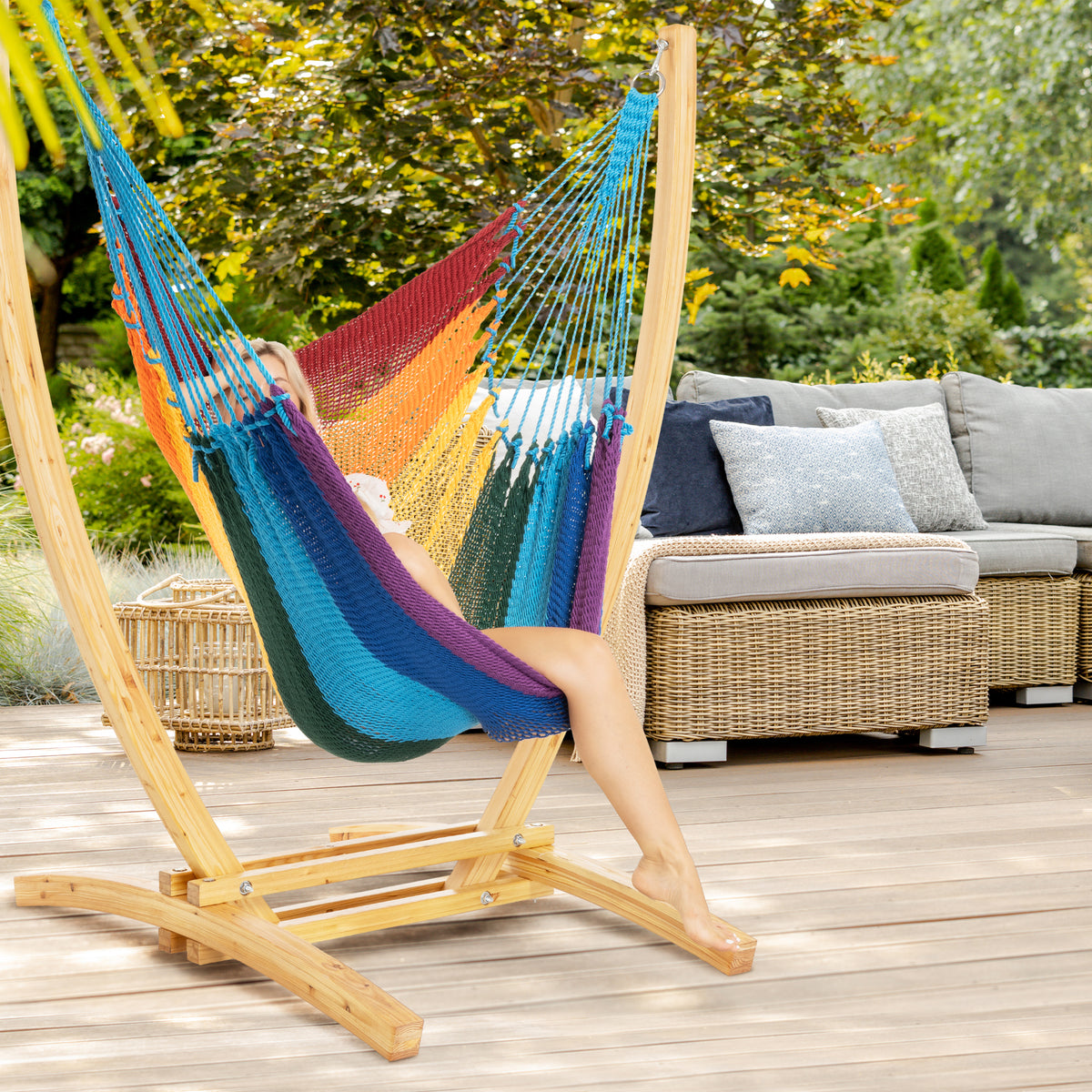Rainbow Jumbo Caribbean Recliner on a wood arc stand on a deck beside a wicker sofa