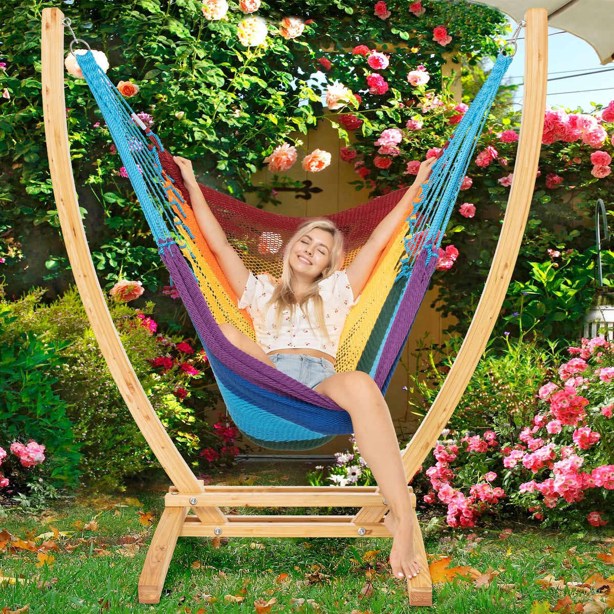 Rainbow Jumbo Caribbean Recliner on a wood arc stand in a garden framed by climbing roses