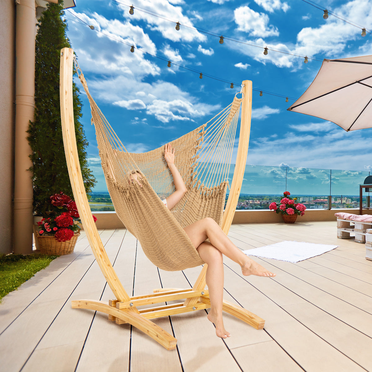 Tan Jumbo Caribbean Recliner on a wood arc stand on a rooftop deck under string lights and a patio umbrella