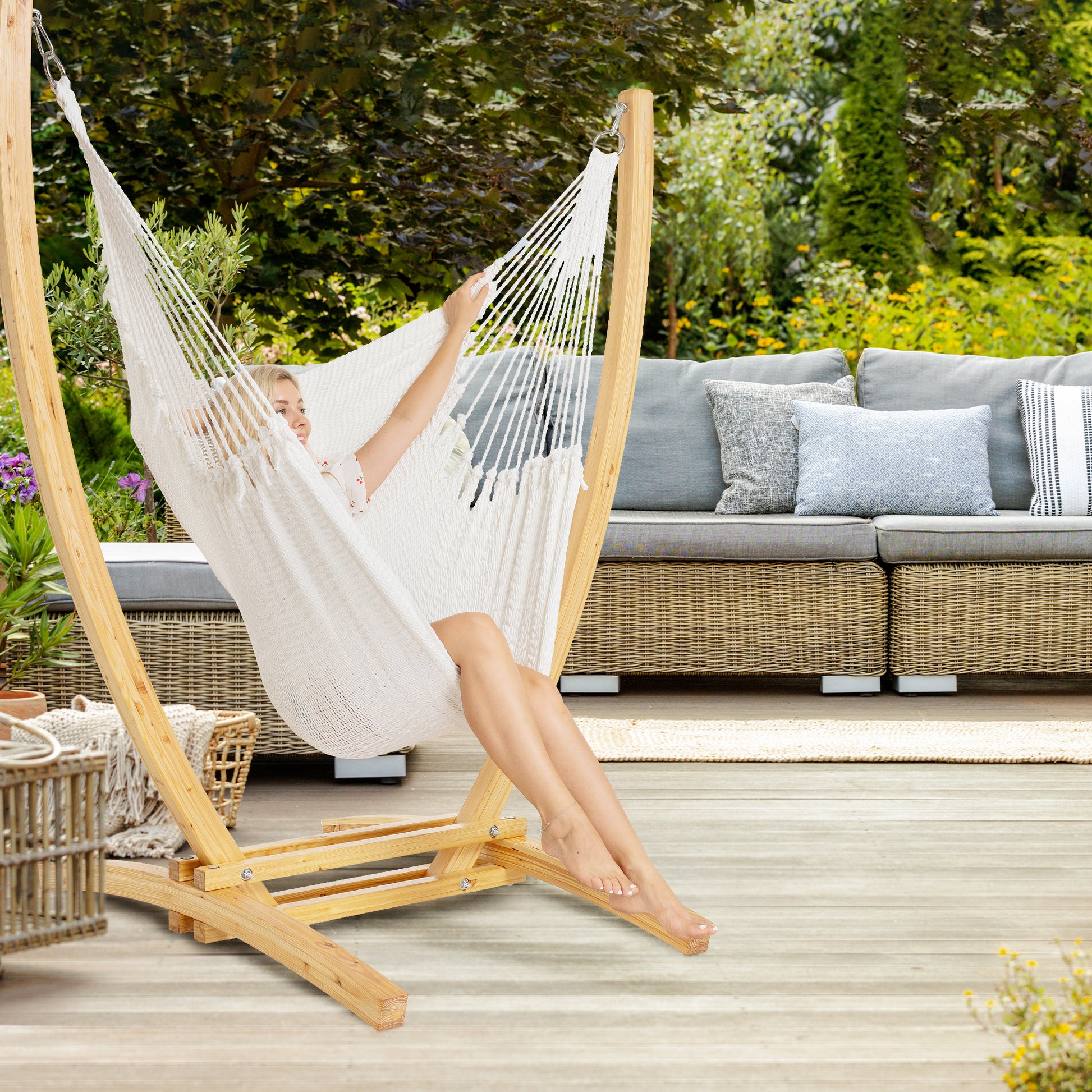 White Jumbo Caribbean Recliner on a wood arc stand on a deck beside a wicker sofa